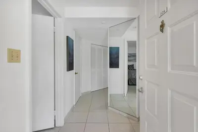 a hallway with a mirror and white walls at Le Frontenac 204 STR-01054 in Sunny Isles Beach