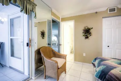 a bedroom with a bed and a chair next to a door at Le Frontenac 205 STR-01057 in Sunny Isles Beach