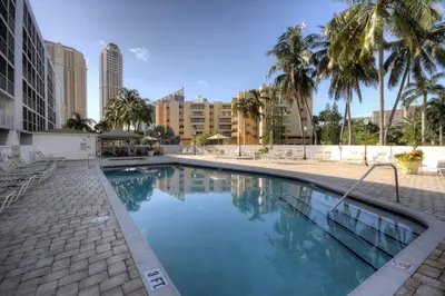 a swimming pool with palm trees and buildings at Le Frontenac 205 STR-01057 in Sunny Isles Beach
