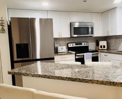 a kitchen with a stainless steel refrigerator and white cabinets at Le Frontenac in Sunny Isles unit 402 STR-03003 in Sunny Isles Beach