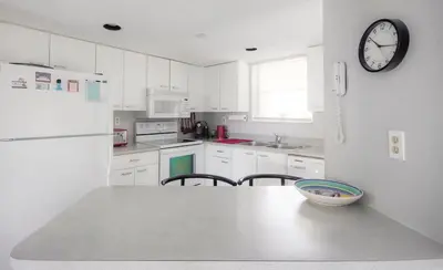 a kitchen with white cabinets and a clock on the wall at Le Frontenac 404 STR-02799 in Sunny Isles Beach