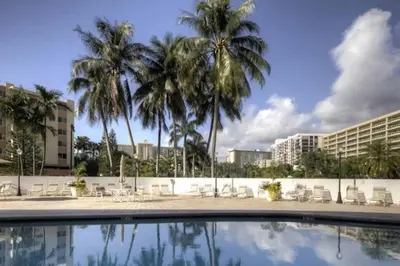 a swimming pool with palm trees and buildings at Le Frontenac 414 STR-01532 in Sunny Isles Beach