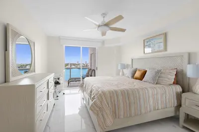 a white bedroom with a bed and a balcony at Le Golden Bay 902 STR-00876 in Sunny Isles Beach