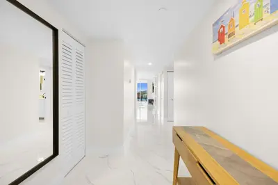 a hallway with white walls and a wooden bench at Le Golden Bay 902 STR-00876 in Sunny Isles Beach