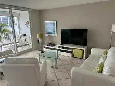 a living room with white furniture and a flat screen tv at Le Laurier in Sunny Isles Beach