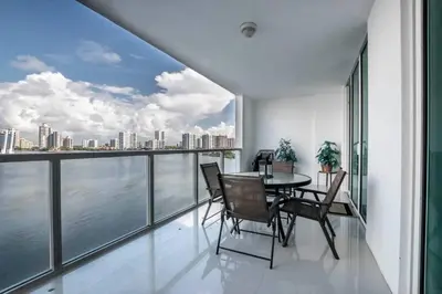 a dining room with a table and chairs on a balcony at Le Marina Bay 1006 STR-01435 in Sunny Isles Beach