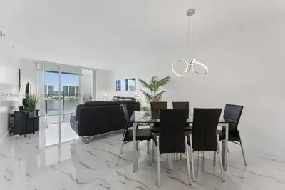 a dining room with a table and black chairs at Marina Bay Club STR-0 in Sunny Isles Beach