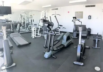 a gym with several treadmills and machines at Marina Bay Club STR-0 in Sunny Isles Beach