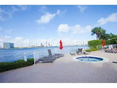 a patio with chairs and a pool next to the water at Marina Bay Club STR-0 in Sunny Isles Beach
