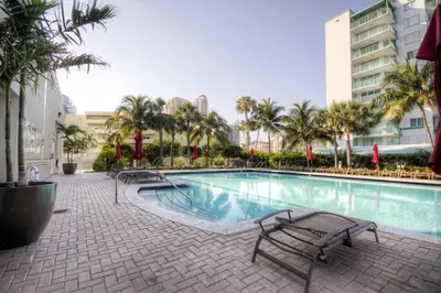 a swimming pool with chairs and palm trees and buildings at Marina Bay Club STR-0 in Sunny Isles Beach