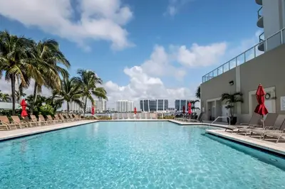 a swimming pool at a resort with chairs and palm trees at Le Marina Bay 1109 STR-01972 in Sunny Isles Beach