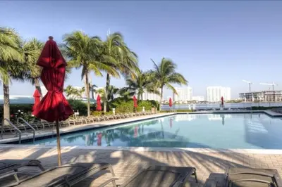 a pool with a red umbrella and chairs and palm trees at Le Marina Bay 310 STR-01478 in Sunny Isles Beach