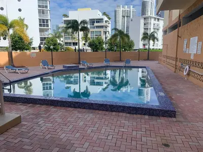 a swimming pool with chairs and buildings in the background at Marbella Tower 706 STR-02489 in Sunny Isles Beach
