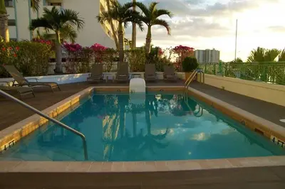 a large swimming pool with chairs and palm trees at Le Montcalm 303 STR-01919 in Sunny Isles Beach