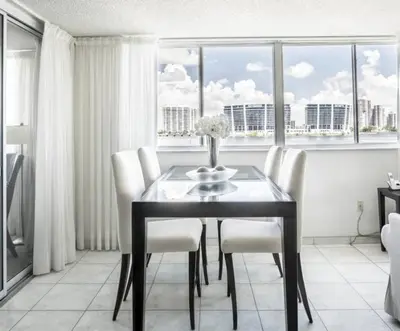 a dining room with a table and chairs and windows at Le Montcalm 303 STR-01919 in Sunny Isles Beach