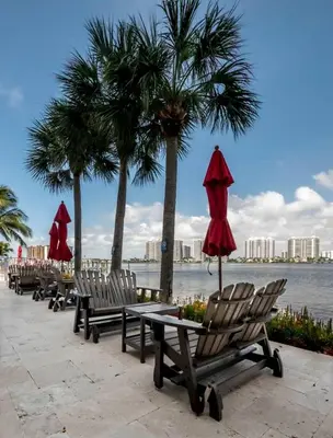 a row of chairs and umbrellas next to the water at Le Marina Bay PH4 STR-01484 in Sunny Isles Beach
