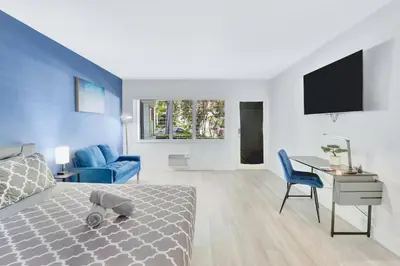 a bedroom with a bed and a desk and a tv at Bright 1BR Miami Beach Apt with 3 Queens & Smart TV in Miami Beach