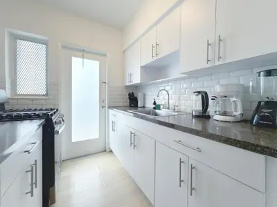 a white kitchen with white cabinets and a sink at 1BR Miami Beach Apt with King plus 2 Queens & Parking in Miami Beach