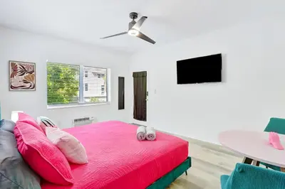 a bedroom with a pink bed and a table at Modern Miami Beach Studio with King Bed in Miami Beach
