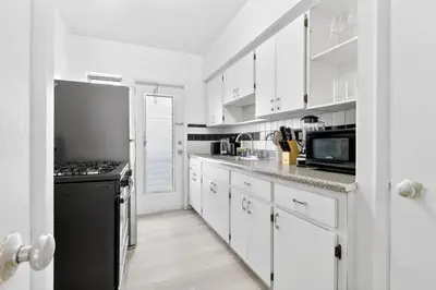 a kitchen with white cabinets and a black stove at Sunny Miami Beach Studio with 2 Queens plus Workspace in Miami Beach