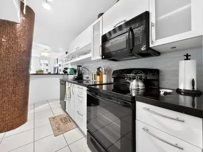 a kitchen with white cabinets and a black stove top oven at Miami Beach Studio with shared Heated Pool & Gym in Miami Beach
