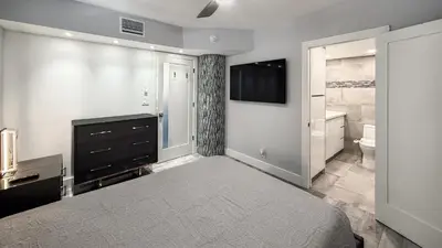 a bedroom with a bed and a television and a bathroom at Great 2BR Condo-DIRECT BEACH ACCESS Pool, Gym and FREE Parking in Hollywood
