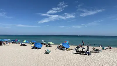 a group of people sitting on a beach with umbrellas at Great 2BR Condo-DIRECT BEACH ACCESS Pool, Gym and FREE Parking in Hollywood