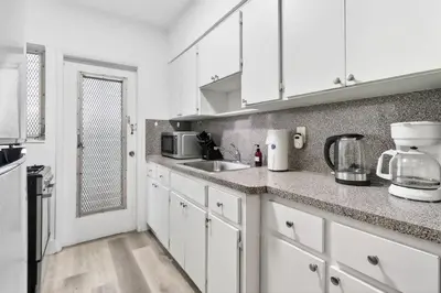 a kitchen with white cabinets and a sink at Cozy Miami Beach Studio with 2 Queens plus Workspace in Miami Beach