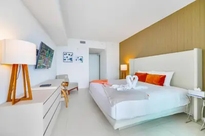 a white bedroom with a large bed and a desk at Modern Beachside Condo W Ocean Views in Hollywood