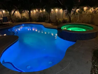 a swimming pool lit up in blue at night at Private Luxe Pool Club Heated Spa in Fort Lauderdale