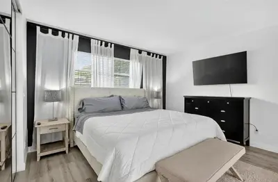 a bedroom with a white bed and a flat screen tv at Spacious 3BR Home with Private Pool in Hollywood in Hollywood