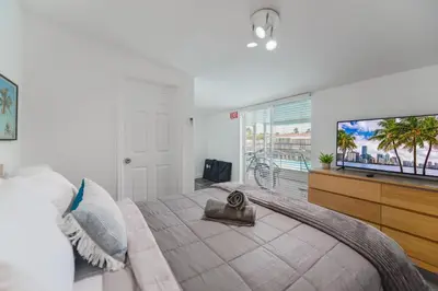 a bedroom with a large bed with a large flat screen tv at Waterfront Pool Home to Few Minutes to Beach in Fort Lauderdale