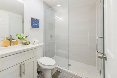 a white bathroom with a shower and a toilet at Waterfront Pool Home to Few Minutes to Beach in Fort Lauderdale