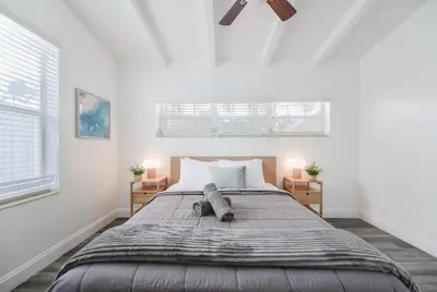 a bedroom with a large bed with two windows at Waterfront Pool Home to Few Minutes to Beach in Fort Lauderdale