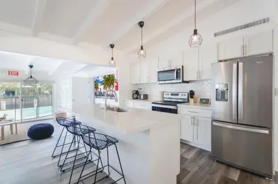 a kitchen with white cabinets and a stainless steel refrigerator at Waterfront Pool Home to Few Minutes to Beach in Fort Lauderdale