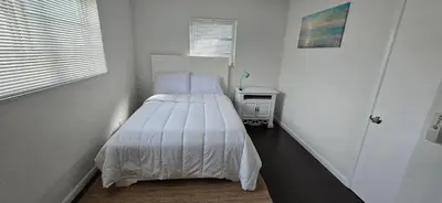 a bedroom with a bed in a white room at Cozy private 2BR Home with Outdoor space and BBQ grill in Hollywood