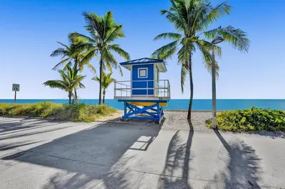a blue lifeguard tower on the beach with palm trees at Desoto Beach Retreat with Heated Pool - By Atlantikos in Hollywood