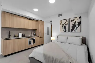 a bedroom with a large bed and a kitchen at Brand New Modern Downtown Studio at Prime Location in Miami