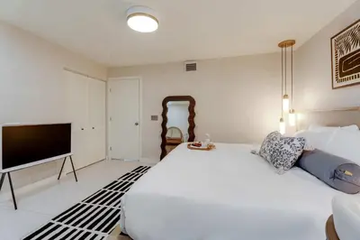 a bedroom with a large white bed and a flat screen tv at Casa Anton- Artist Home Pool & Rooftop Hot Tub in Miami