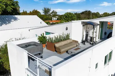 an outdoor patio with a couch on a white building at Casa Anton- Artist Home Pool & Rooftop Hot Tub in Miami