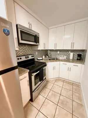 a kitchen with white cabinets and a stove and microwave at Best location in Coconut Grove in Miami