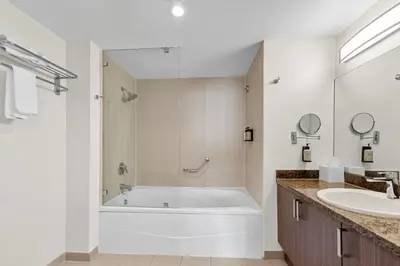 a white bathroom with a tub and a sink at Arya Hotel & Suites in Miami