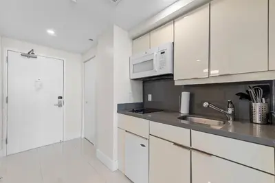 a white kitchen with a sink and a microwave at Arya Hotel & Suites in Miami