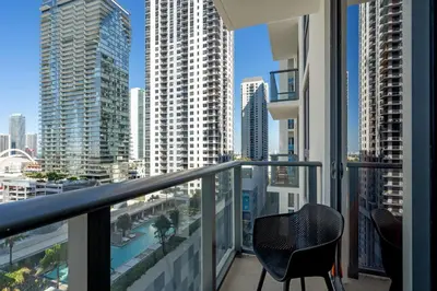 a balcony with two chairs and a view of a city at Stylish Urban 1BR Downtown Rooftop Pool & Views in Miami