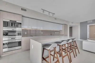 a kitchen with stainless steel appliances and stools at Prime Oceanfront 3BR Mansion in the Sky in Hollywood