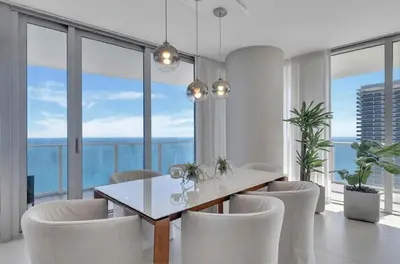 a dining room with a table and chairs and large windows at Prime Oceanfront 3BR Mansion in the Sky in Hollywood