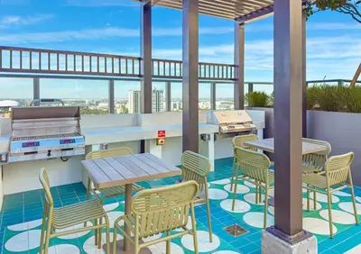 a rooftop patio with tables and chairs and a grill at Modern MIA Worldcenter Studio with Balcony Pool & Gym in Miami