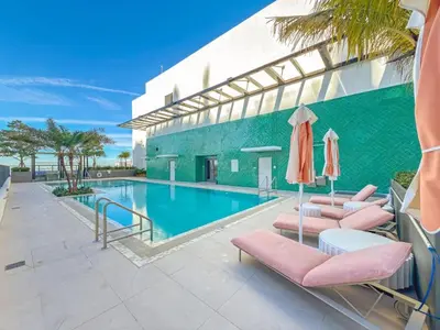 a pool with chairs and umbrellas next to a building at Modern MIA Worldcenter Studio with Balcony Pool & Gym in Miami
