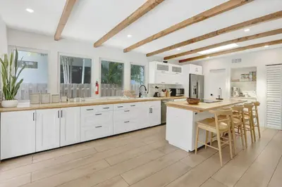 a kitchen with white cabinets and a table and chairs at Casa in Tropic Paradise with Pool and BBQ in Biscayne Park