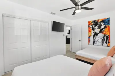 a white bedroom with two beds and a ceiling fan at Spacious Miami 4BR Retreat with Pool & BBQ in Miami